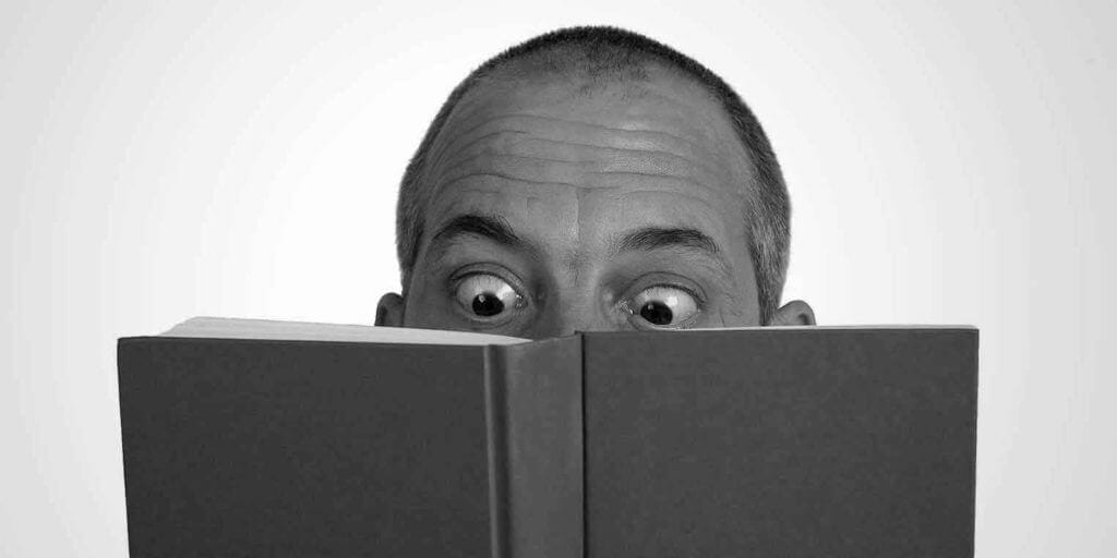 foto decorativa, homem arregalando olhos ao ler livro